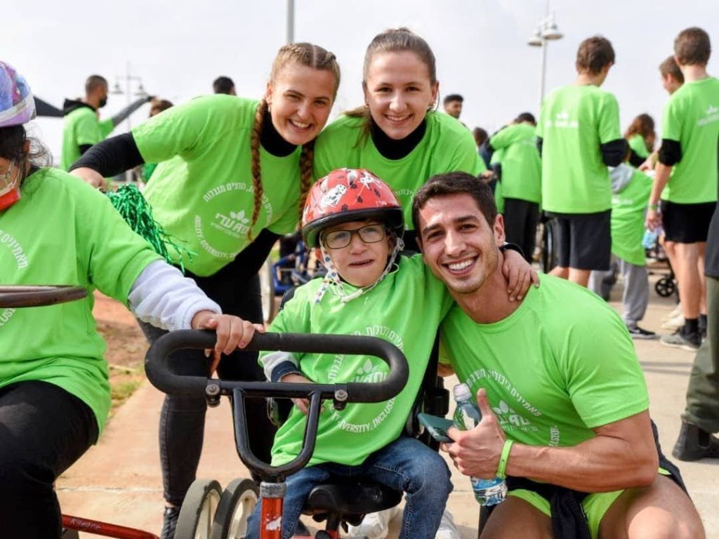 Little boy on bike and volunteers ילד על אופניים עם מתנדבים
