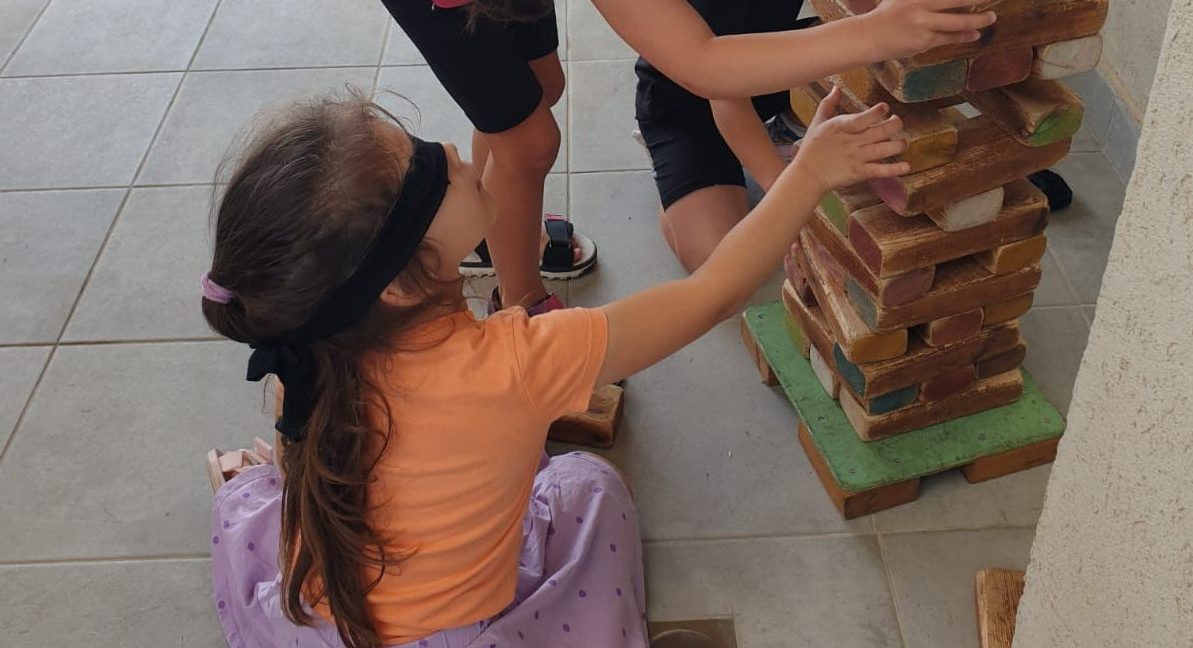 ילדה עם עיניים מכוסות בונה בקוביות Girl with blindfold builds with blocks