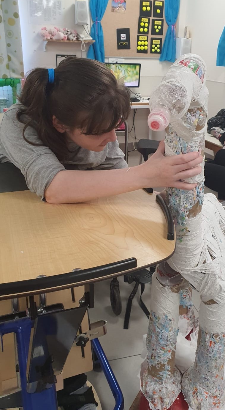 Girl in wheelchair making a paper mache giraffe ילדה בכסא גלגלים מיצרת ג'ירפה מעיסת נייר