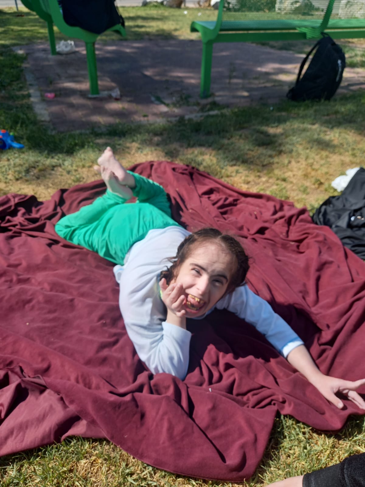 בחורה עם מגלויות על שמיכה בפארק Girl with disabilities on a blanket in the park