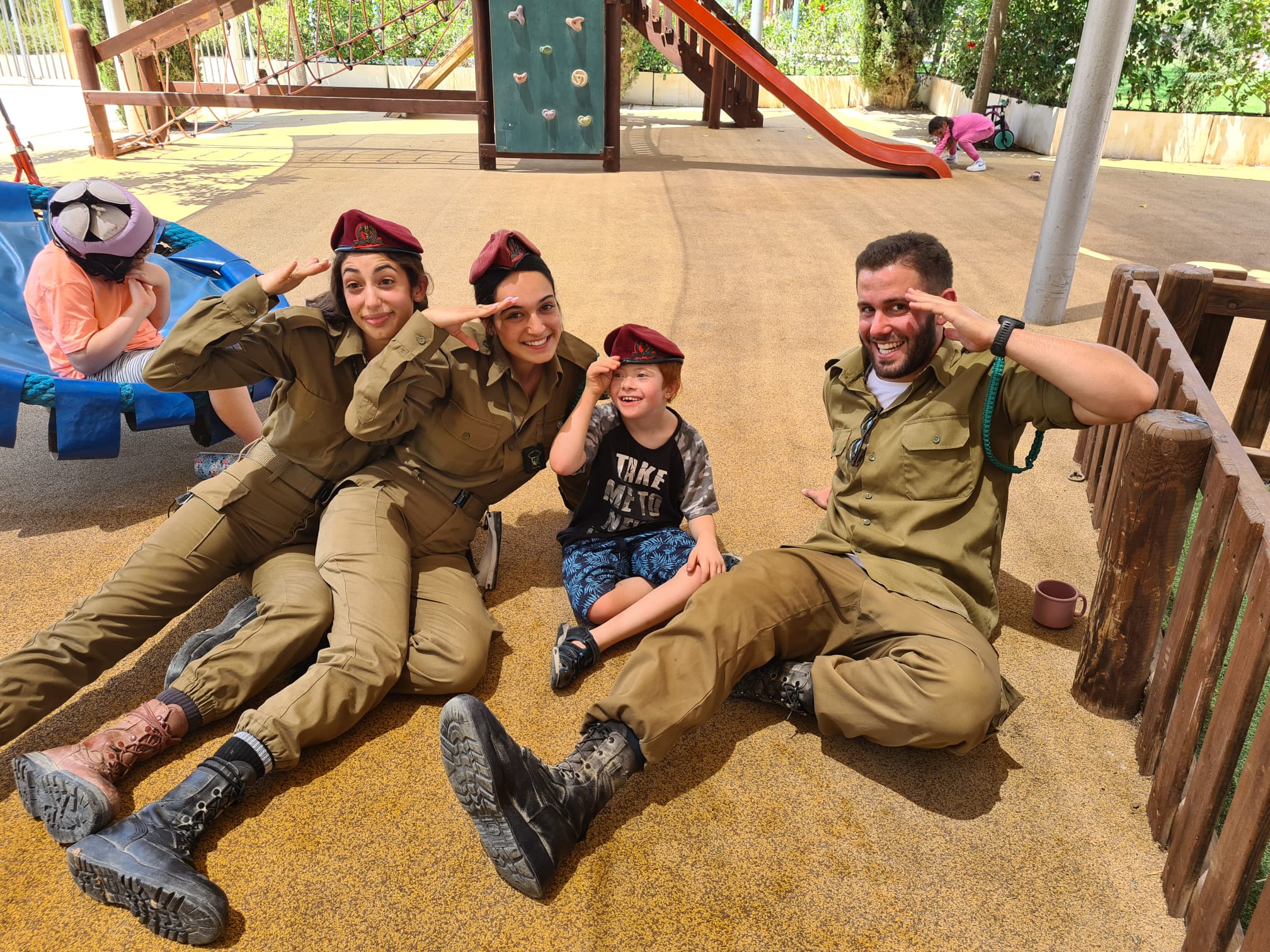 Child with disabilities wearing soldier's beret salutes with soldiers ילד עם מגבלויות חבוש כובע חייל מצדיע עם חיילים