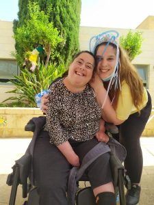 אישה ליד בחורה בכסא גלגלים woman next to adolescent in wheelchair