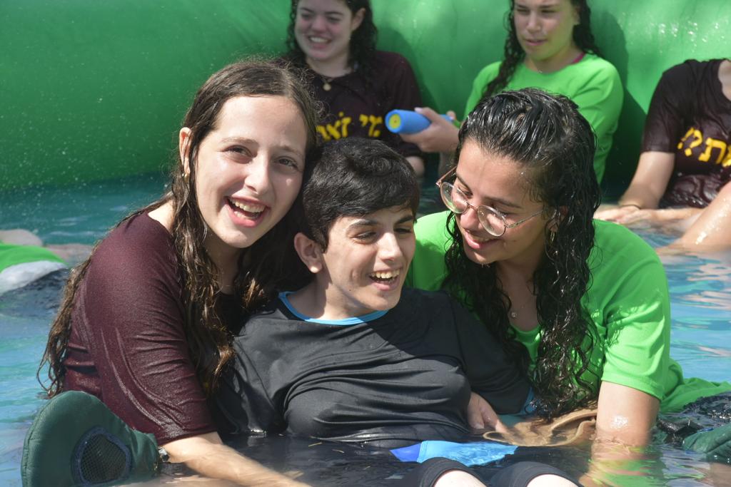 Girl with disabilities in pool with volunteers בחורה עם מגבלויות בבריכה עם מתנדבות