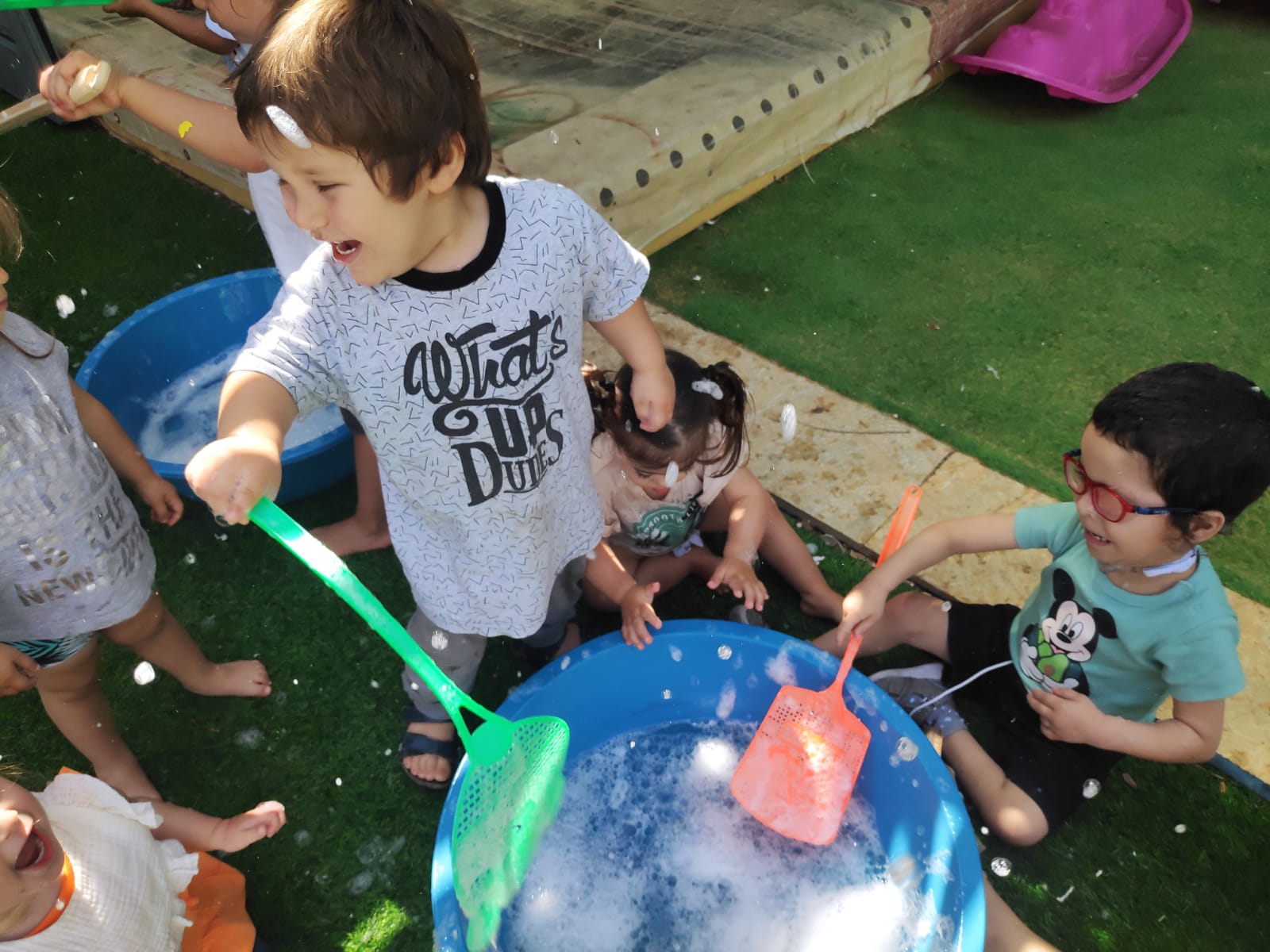 ילדים משחקים עם גיגית עם בועות סבון Children playing with a bin of water and soap bubbles