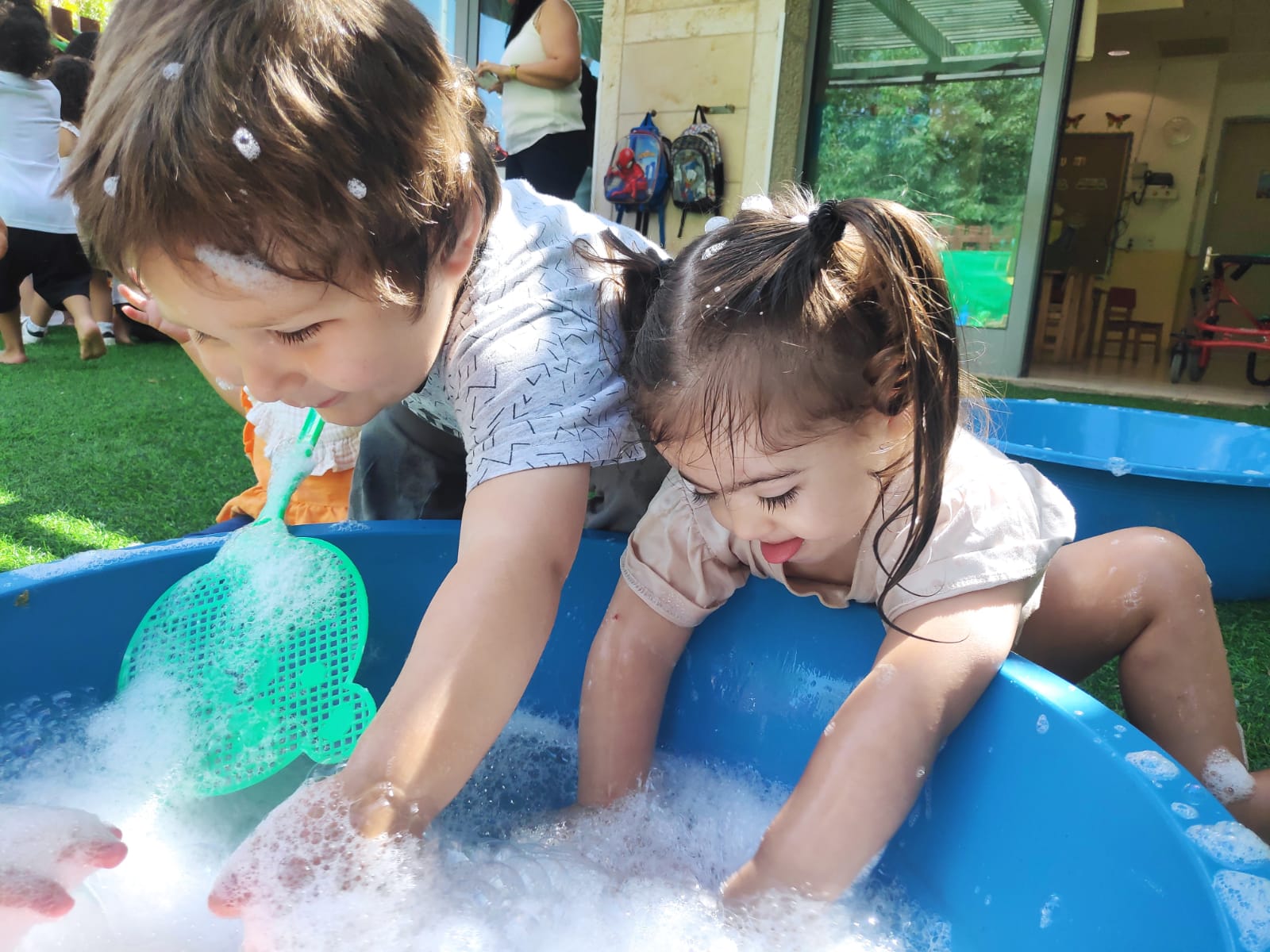ילדים משחקים עם גיגית עם בועות סבון Children playing with a bin of water and soap bubbles