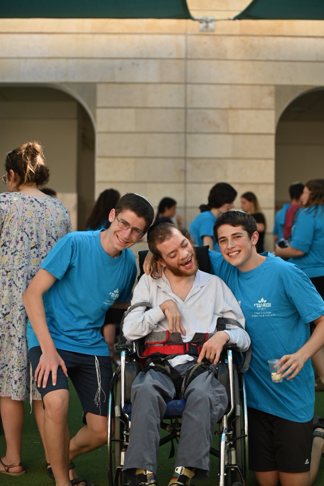 שני מתנדבים ובחור בכסא גלגלים Two volunteers and a young man in a wheelchair