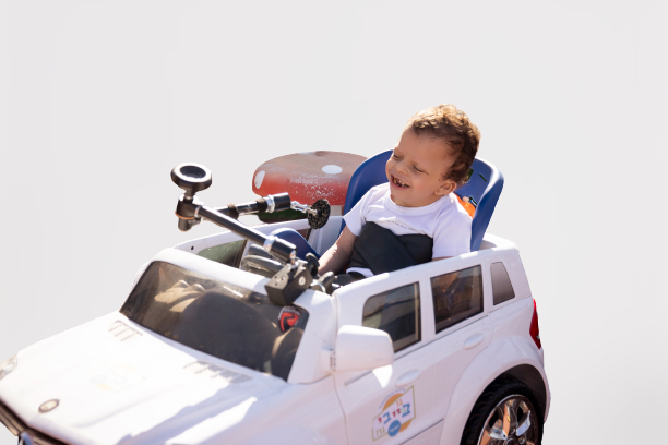 ילד בכסא גלגלים דומה למכונית Young boy in a wheelchair fashioned like a car.