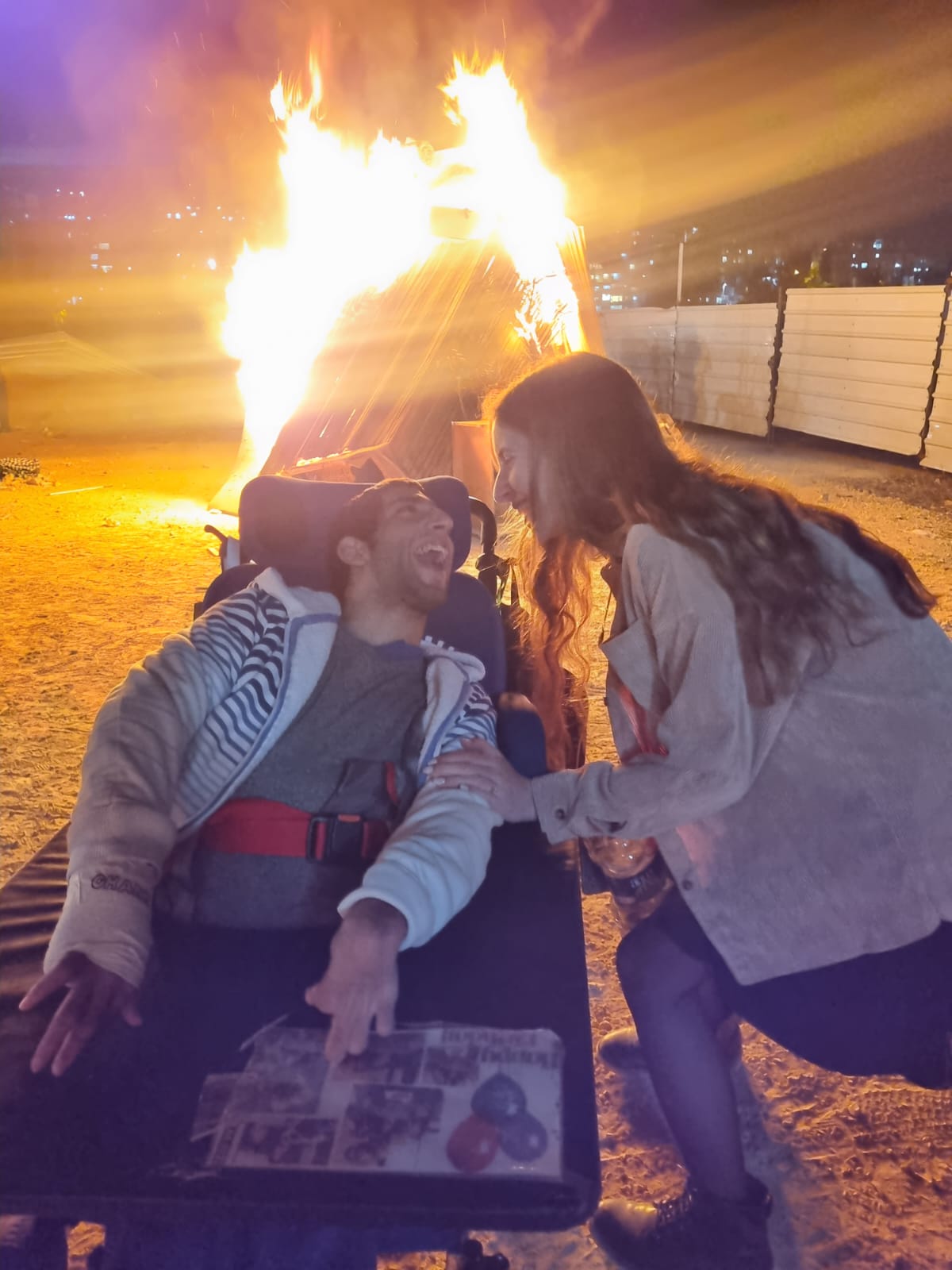 Young man in wheelchair in front of a bonfire בחור בכסא גלגלים לפני מדורה