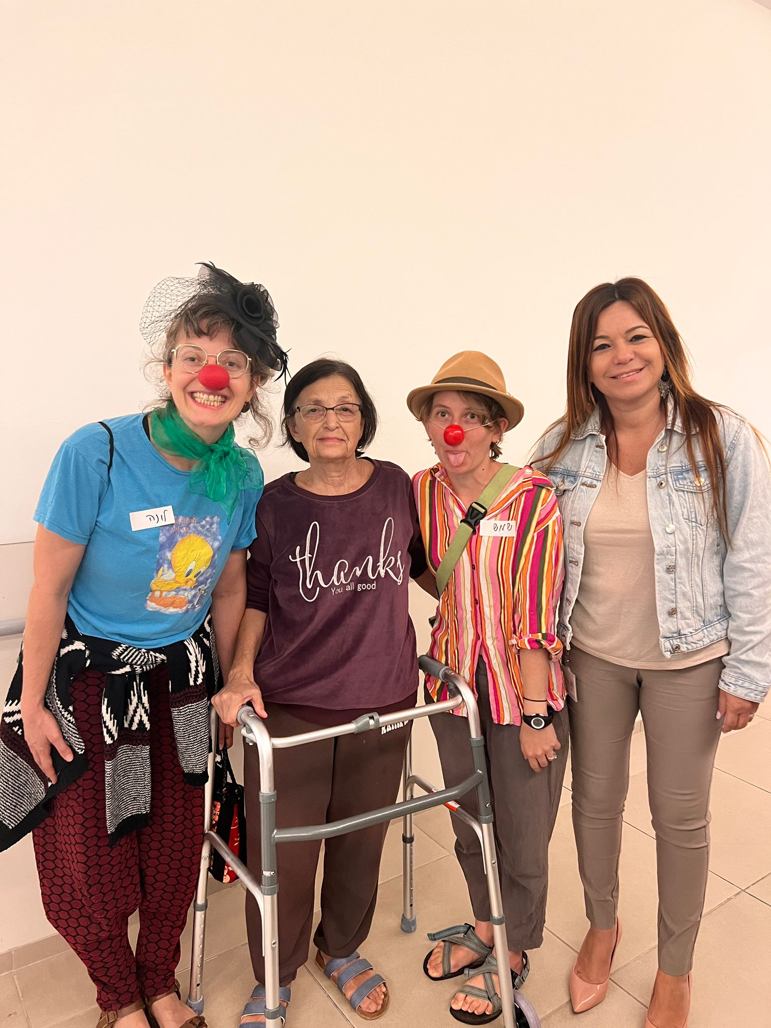 אישה עם הליכון עומדת עם ליצנים רפואיים ואשת צוות Woman with a walker standing next to medical clowns and employee