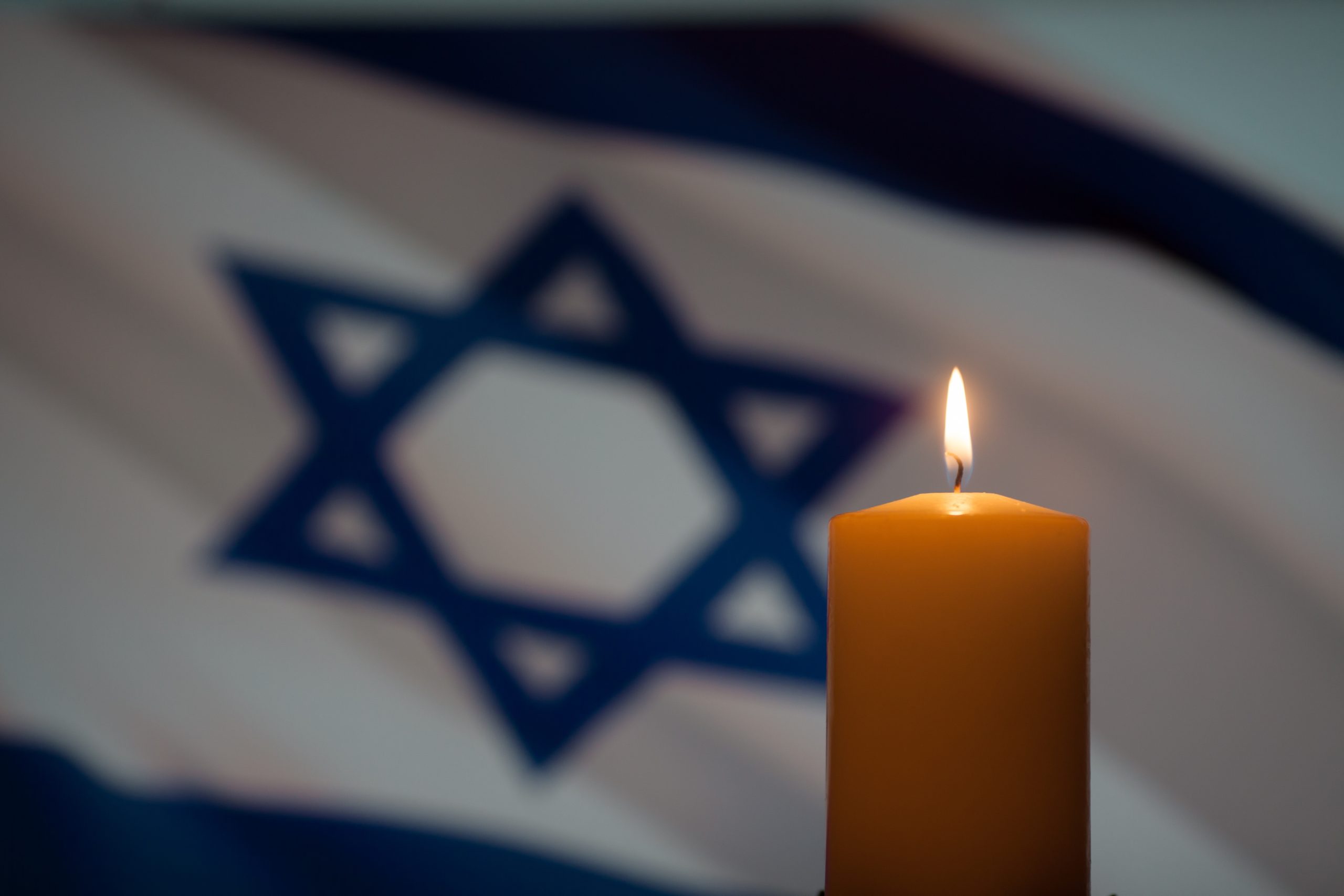 Yahrzeit candle with Israeli flag in background נר נשמה עם דגל ישראל ברקע