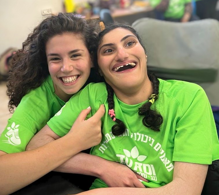 Volunteer and girl with disabilities laughing מתנדבת ובחורה עם מגבלויות צוחקות