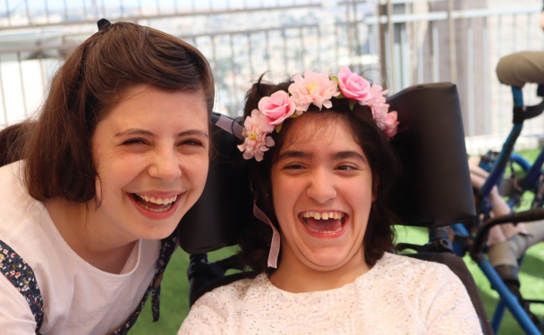 Woman and girl with disabilities in wheelchair laughing אישה וילדה עם מגבלויות בכסא גלגלים צוחקים